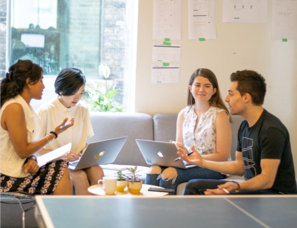 A group of people working and talking at a round table.