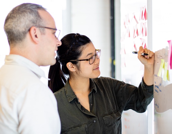 People placing stickies on a whiteboard.